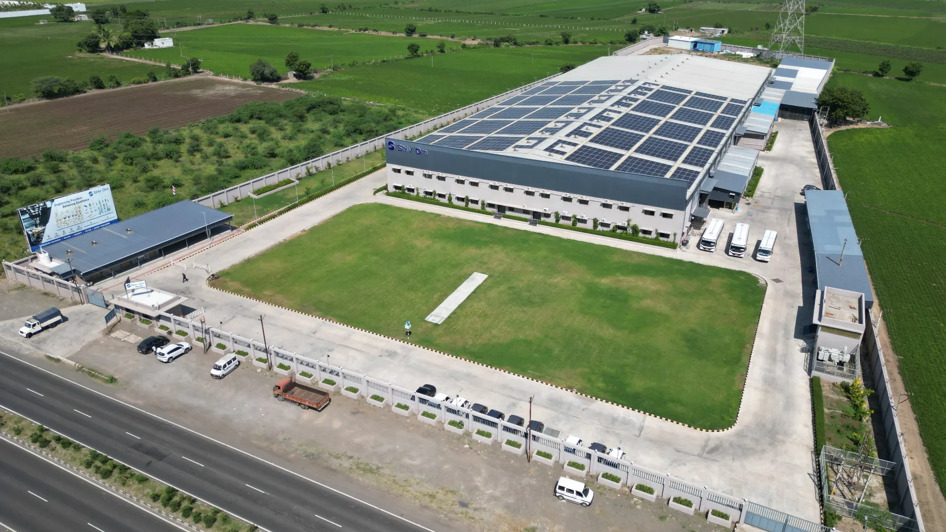 Aerial view of the Shiv Om E-Tec manufacturing plant with solar panels across the roof, beside the Jamnagar-Rajkot Highway