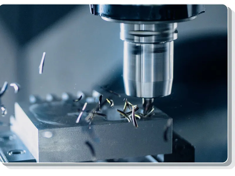 CNC milling cutter machining a metal block with chips flying